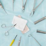Top view of assorted dental surgical instruments on a blue background, sterile and ready for use.